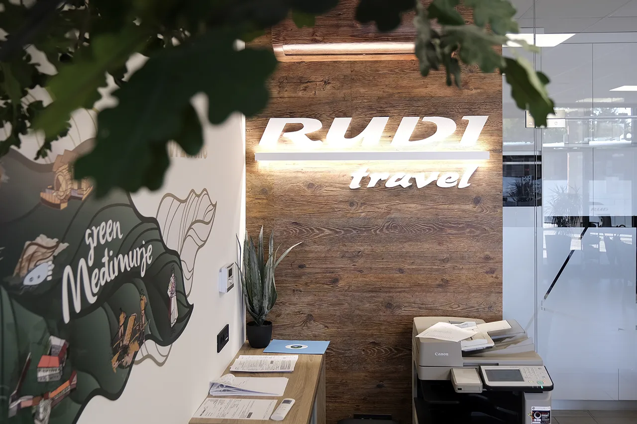 Svijetleći natpis Rudi Travel na drvenoj oblozi poslovnice